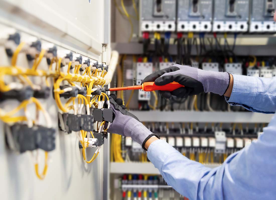 Electrical Contractor Insurance - Close-up View of an Electrician Working to Connect Electrical Wires of the Electrical System Switchboard in the Control Cabinet
