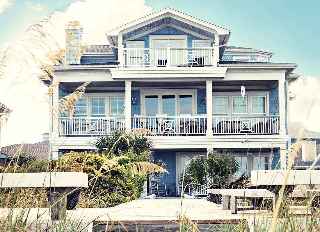 Secondary Home Insurance - Luxury Beach Front Vacation Home with Multiple Balconies and Private Dock in the Summer at Dusk